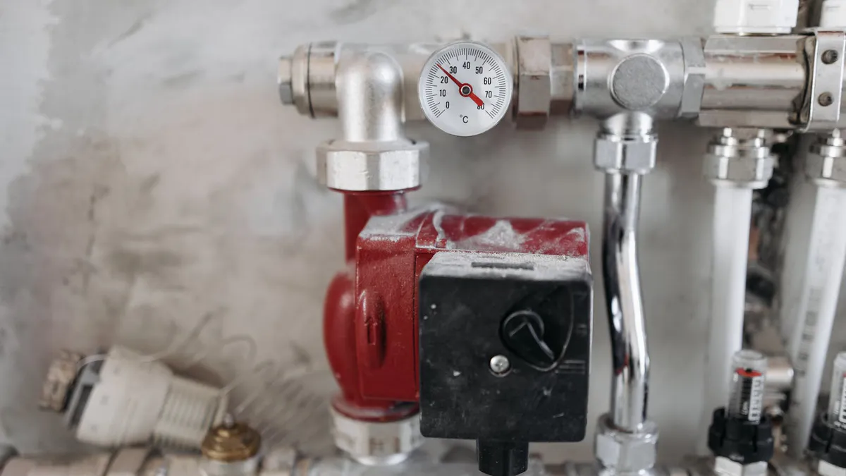Pressure gauge mounted on steel plumbing pipes showing a well water system pressure reading