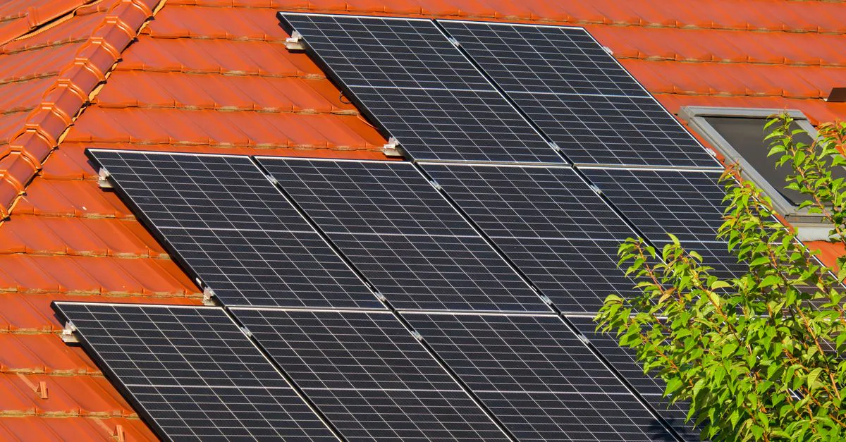 Close-up of dark blue solar panels mounted in rows on a tiled residential roof in bright sunlight