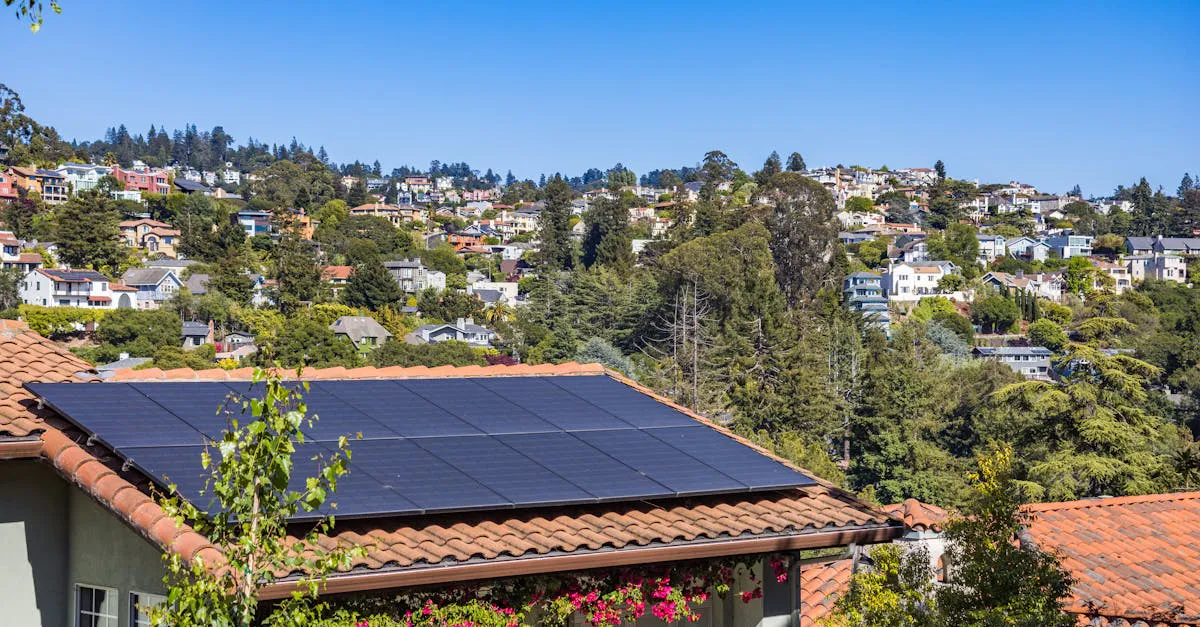 Rooftop solar panels on a single-story suburban house surrounded by green trees under a clear sky