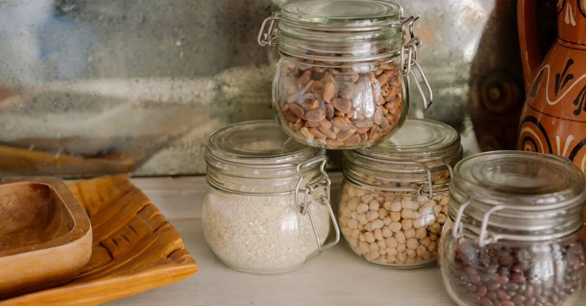 Glass jars filled with white rice, dried beans, and chickpeas lined up on a wooden kitchen counter