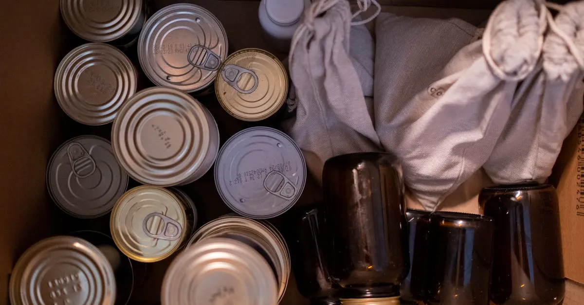 Top-down view of a cardboard box packed with canned goods, glass jars, and cloth sacks of dry goods