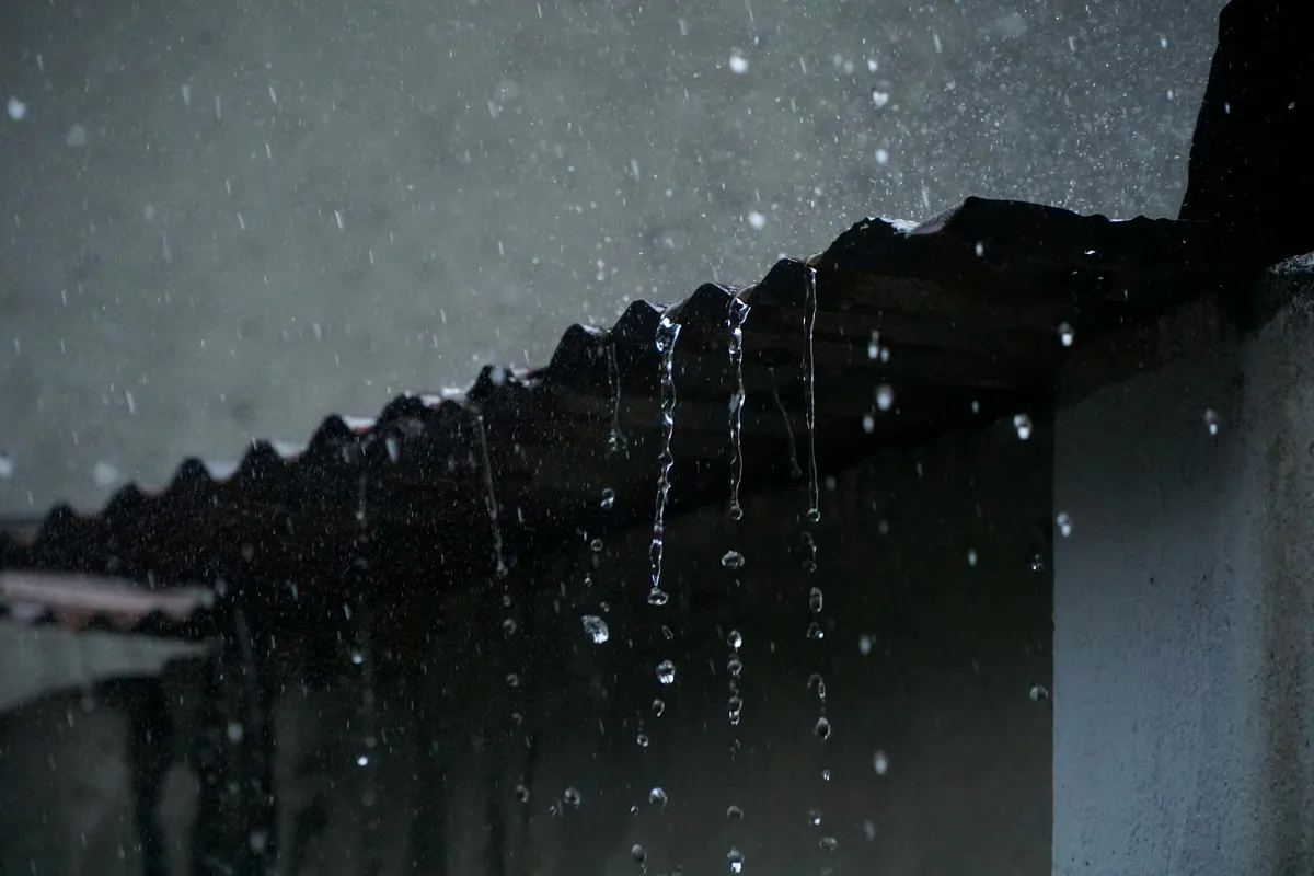 Rainwater running off the edge of a corrugated metal roof during a storm